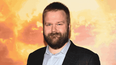 A Man With A Beard Is Wearing A Blue Shirt And A Black Jacket GIF