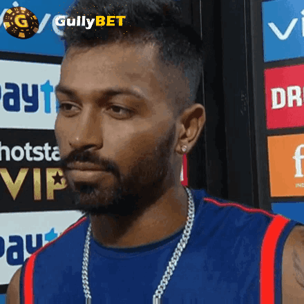 A Man With A Beard Is Wearing A Blue Shirt And A Gold Chain GIF