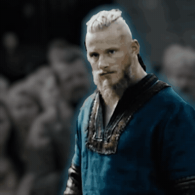 A Man With A Beard Is Wearing A Blue Shirt And Looking At The Camera GIF
