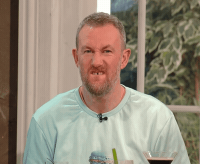 A Man With A Beard Is Wearing A Blue Shirt With A Microphone On His Neck GIF