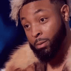 A Man With A Beard Is Wearing A Fur Coat And Looking At The Camera . GIF