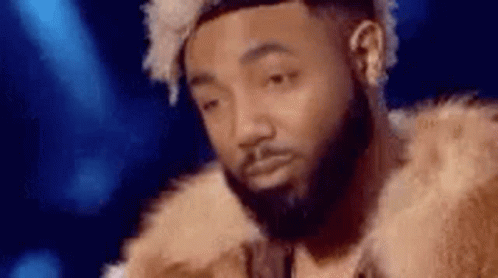 A Man With A Beard Is Wearing A Fur Coat And Making A Funny Face . GIF