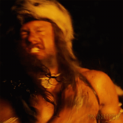 A Man With A Beard Is Wearing A Fur Hat With A Wolf Head GIF