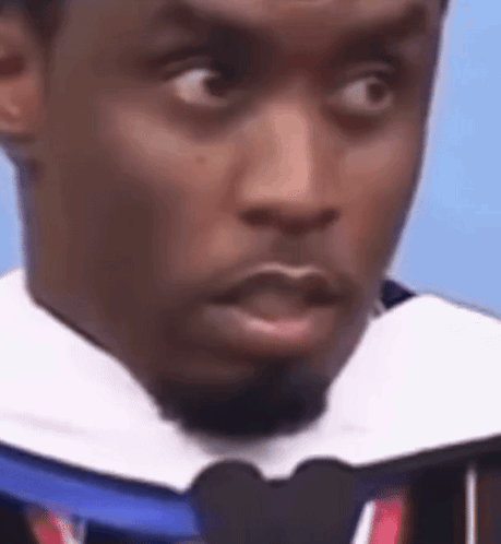 A Man With A Beard Is Wearing A Graduation Cap And Tie . GIF