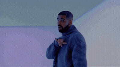 A Man With A Beard Is Wearing A Gray Sweater And Pointing At Something . GIF