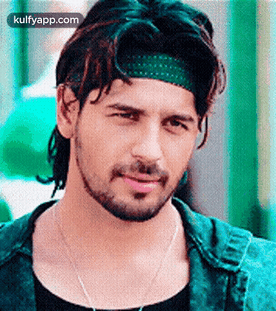 A Man With A Beard Is Wearing A Green Headband And A Black Shirt . GIF