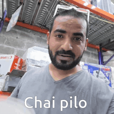 A Man With A Beard Is Wearing A Grey Shirt That Says Chai Pilo On The Front GIF