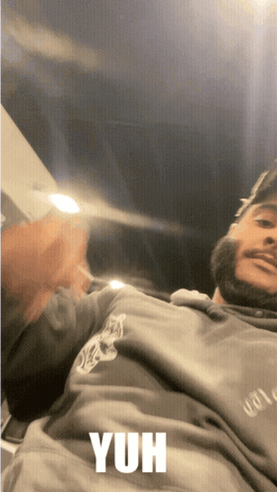A Man With A Beard Is Wearing A Grey Sweatshirt With The Word Yuh On It GIF