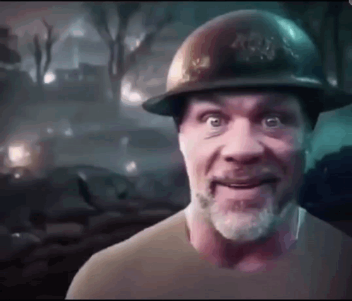 A Man With A Beard Is Wearing A Hard Hat And Smiling . GIF
