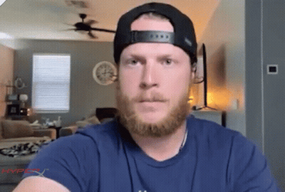A Man With A Beard Is Wearing A Hat And A Blue Shirt That Says Hyperx On It GIF