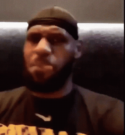 A Man With A Beard Is Wearing A Hat And Sunglasses While Sitting On A Couch . GIF