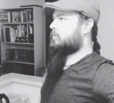 A Man With A Beard Is Wearing A Hat And Taking A Selfie . GIF