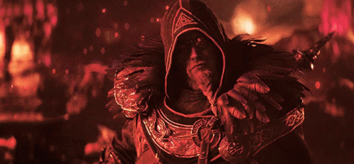 A Man With A Beard Is Wearing A Hooded Cape With Feathers On It GIF