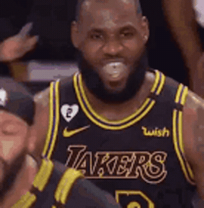 A Man With A Beard Is Wearing A Lakers Jersey And Smiling . GIF