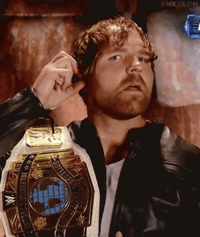 A Man With A Beard Is Wearing A Leather Jacket And Holding A Wrestling Championship Belt . GIF