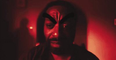 A Man With A Beard Is Wearing A Mask With A Cross On His Face GIF