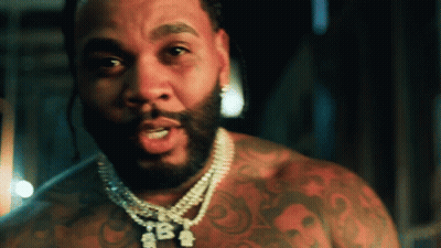 A Man With A Beard Is Wearing A Necklace That Says Tba On It GIF