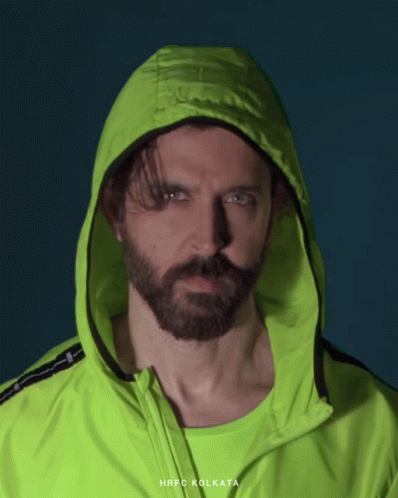 A Man With A Beard Is Wearing A Neon Green Jacket With The Word Kolkata On It GIF