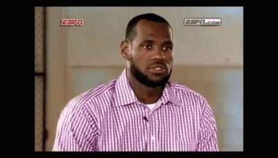 A Man With A Beard Is Wearing A Pink And White Striped Shirt And Talking To A Microphone . GIF