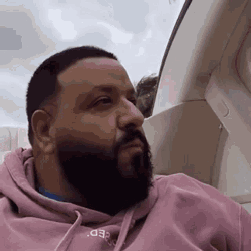 A Man With A Beard Is Wearing A Pink Hoodie That Says Speed GIF