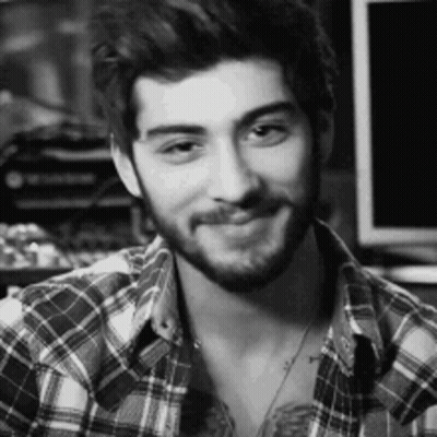 A Man With A Beard Is Wearing A Plaid Shirt And Smiling . GIF