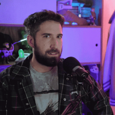 A Man With A Beard Is Wearing A Plaid Shirt With Stussy On It GIF