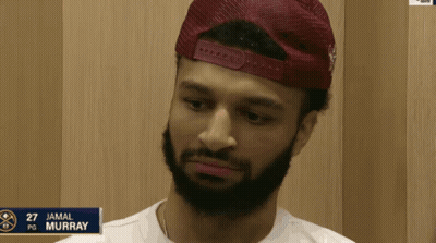 A Man With A Beard Is Wearing A Red Hat And The Name Jamal Murray Is On A Sign GIF