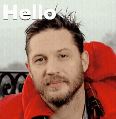 A Man With A Beard Is Wearing A Red Jacket And Smiling . GIF
