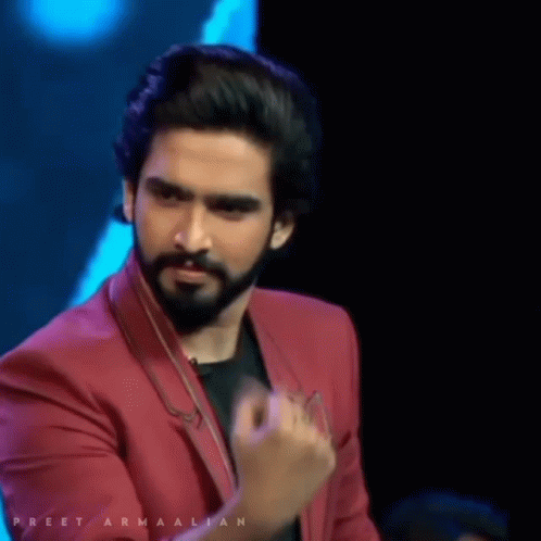 A Man With A Beard Is Wearing A Red Jacket With The Name Preet Armaalian Written On It GIF