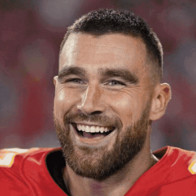 A Man With A Beard Is Wearing A Red Jersey And Smiling . GIF