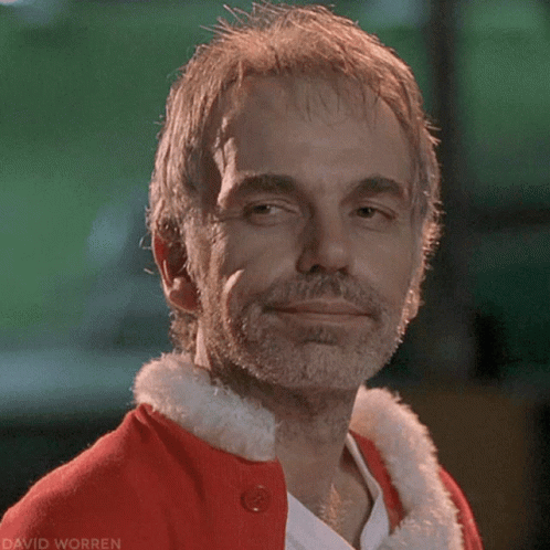 A Man With A Beard Is Wearing A Red Santa Claus Outfit GIF
