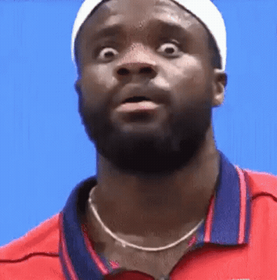 A Man With A Beard Is Wearing A Red Shirt And A White Headband And Making A Funny Face . GIF
