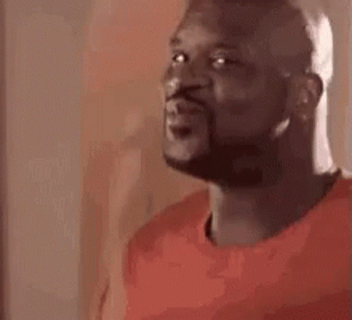 A Man With A Beard Is Wearing A Red Shirt And Looking At The Camera . GIF