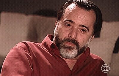 A Man With A Beard Is Wearing A Red Shirt With The Letter O On The Bottom Right GIF