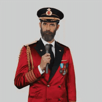 A Man With A Beard Is Wearing A Red Suit And Hat And Making A Funny Face . GIF
