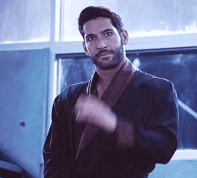 A Man With A Beard Is Wearing A Robe And Waving His Hand In Front Of A Window . GIF