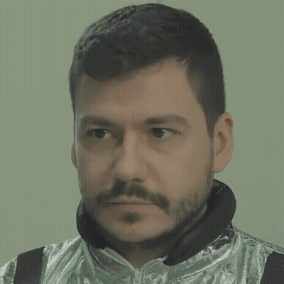 A Man With A Beard Is Wearing A Silver Jacket And Black Headphones GIF