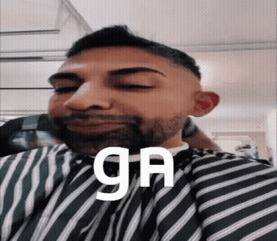 A Man With A Beard Is Wearing A Striped Cape And The Word Ga Is On His Face GIF