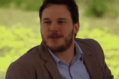 A Man With A Beard Is Wearing A Suit And A Blue Shirt And Is Smiling . GIF