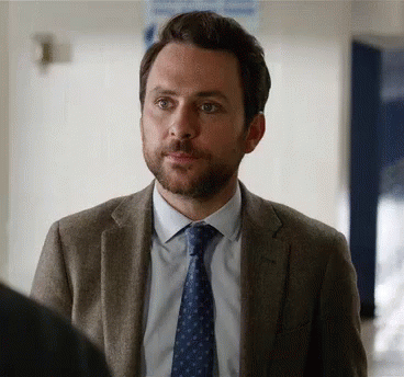 A Man With A Beard Is Wearing A Suit And Tie And Looking At Something . GIF