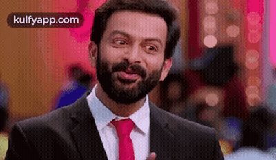 A Man With A Beard Is Wearing A Suit And Tie . GIF