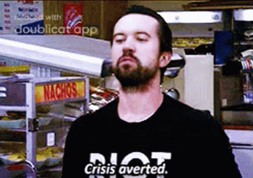 A Man With A Beard Is Wearing A T-Shirt That Says `` Not Crisis Averted . '' GIF