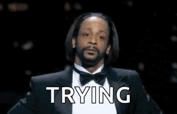 A Man With A Beard Is Wearing A Tuxedo And Bow Tie And Says `` Trying '' . GIF