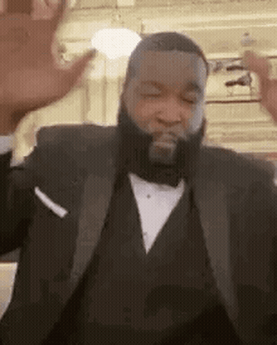 A Man With A Beard Is Wearing A Tuxedo And Dancing . GIF