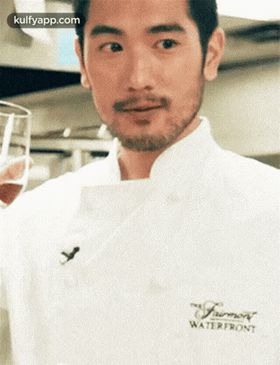 A Man With A Beard Is Wearing A White Chef 'S Coat And Holding A Glass . GIF