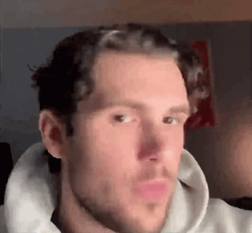 A Man With A Beard Is Wearing A White Hoodie And Making A Funny Face GIF