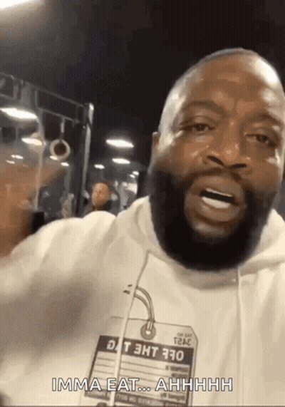 A Man With A Beard Is Wearing A White Hoodie With A Tag That Says ' Imma Eat ' On It . GIF