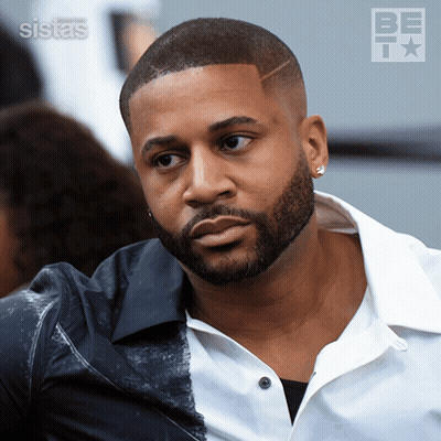 A Man With A Beard Is Wearing A White Shirt And A Black Shirt GIF