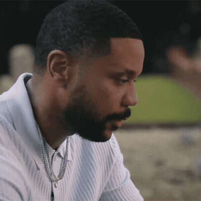 A Man With A Beard Is Wearing A White Shirt And A Gold Chain Around His Neck GIF