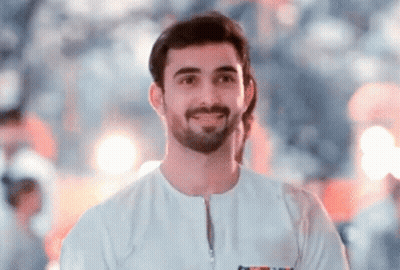 A Man With A Beard Is Wearing A White Shirt And Smiling For The Camera . GIF